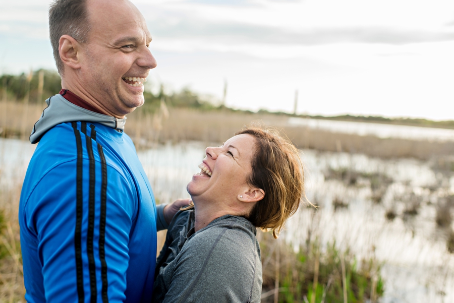 A couple in love laugh on the beach during their cape may engagement session.